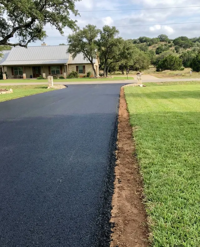 New asphalt driveway with a fresh edge along green grass and live oaks