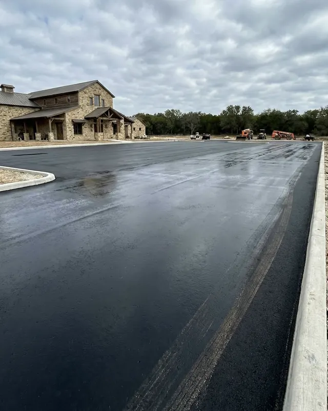 Freshly paved commercial parking lot beside a stone building